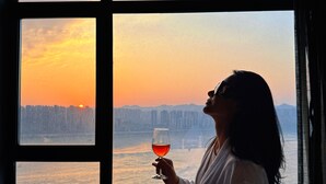 A person sitting by a window with a view of a sunset over a body of water. - Chongqing jiayu emperor hotel  (Chongqing)