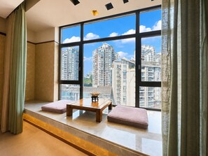 Una habitación con un ventanal grande, una mesa de madera y dos cojines rosas.