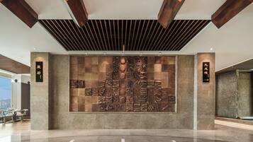 A modern lobby with a large wall mural, polished floor, and wooden ceiling beams.