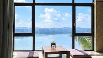 Ein Zimmer mit großem Fenster und Blick auf einen Fluss und die Stadt.