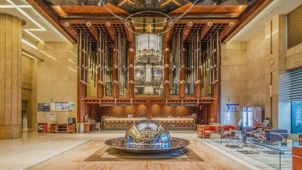 A spacious lobby with a large, ornate chandelier, a central reflective water feature, and a seating area with a checkered pattern. - Chongqing jiayu emperor hotel  (Chongqing)