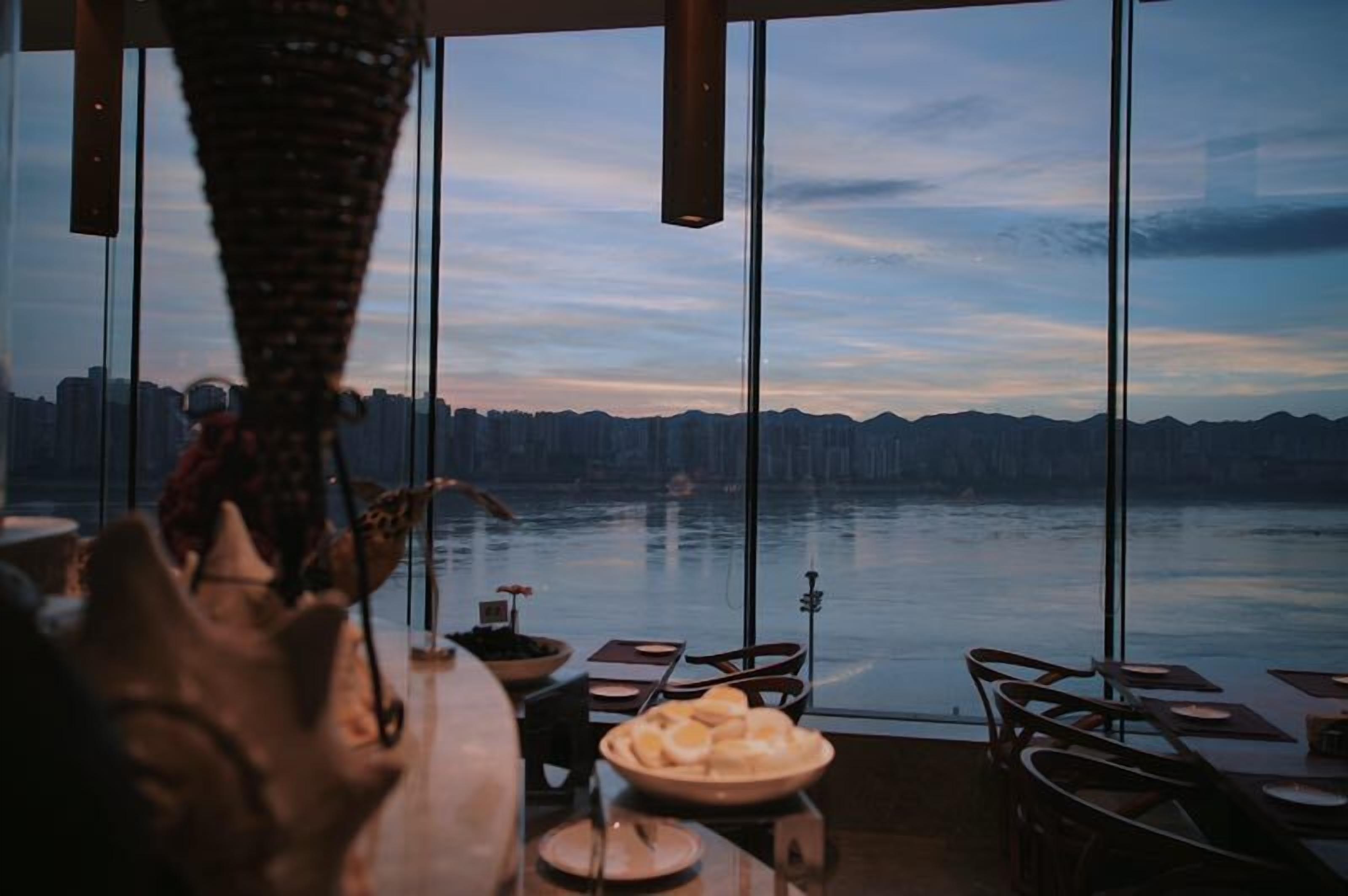 A dining area with a view of a body of water and a city skyline.