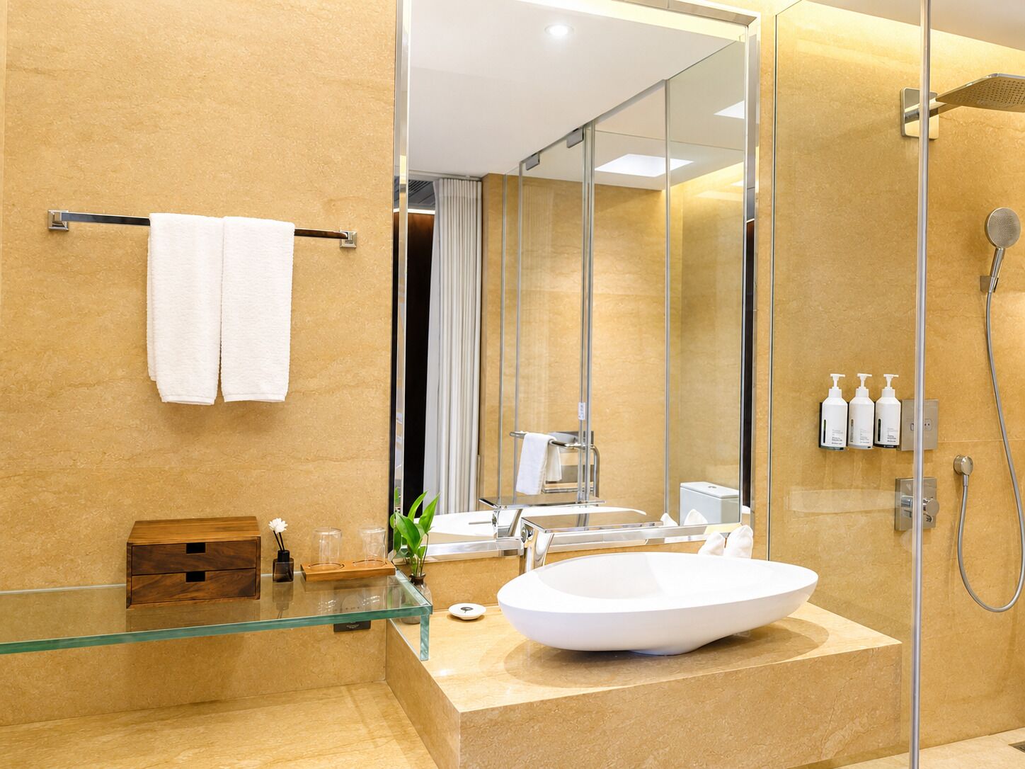 A modern bathroom with a glass shower enclosure, a white sink, and a towel rack.