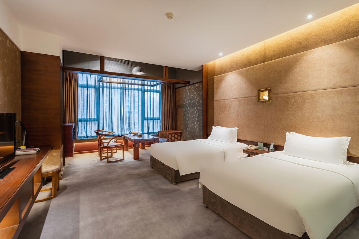 A hotel room with two beds, a desk, and a chair.