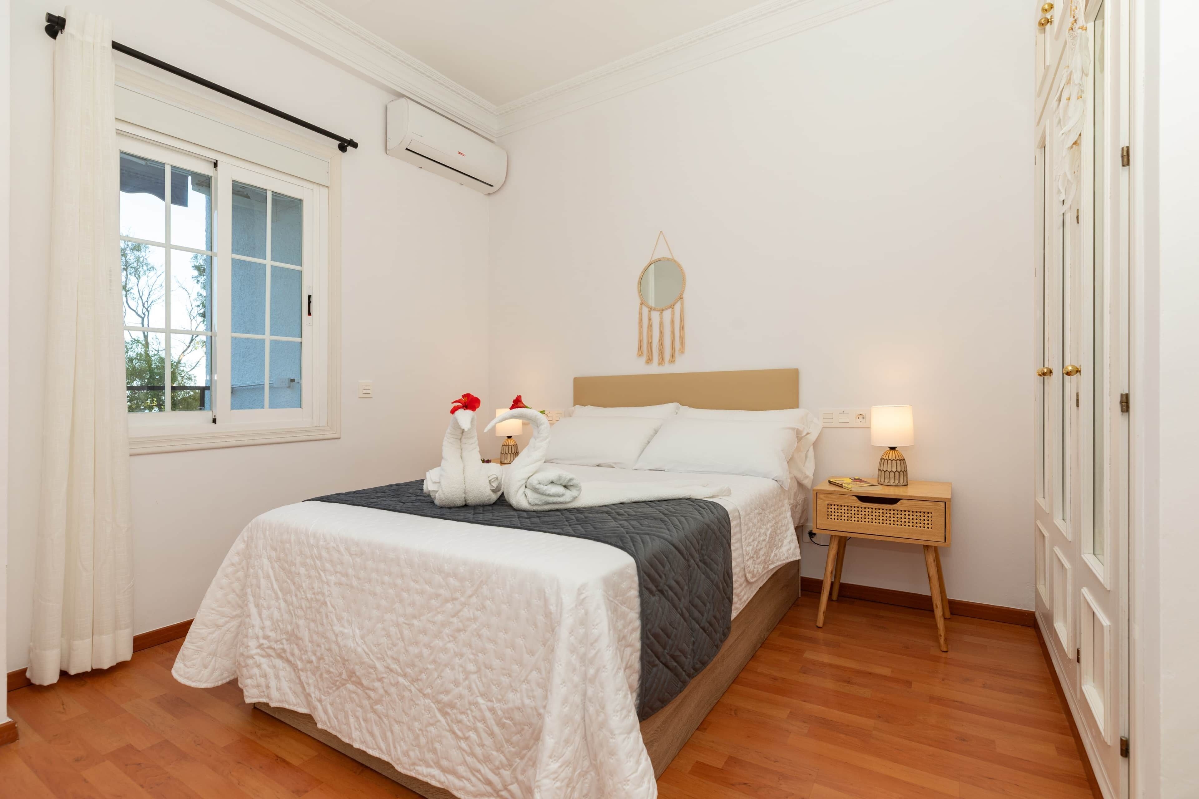 A neatly arranged bedroom with a bed, bedside table, and a window with curtains.