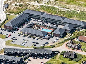 An aerial view of a hotel with multiple buildings, a swimming pool, and a parking lot.
