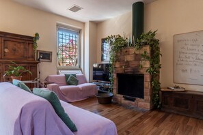 A cozy living room with a fireplace, wooden furniture, and a large window with a view.