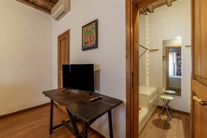 Une pièce comprenant un bureau en bois, un téléviseur à écran plat et une petite table.