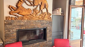 Un salon avec une cheminée en pierre, deux fauteuils rouges et un téléviseur.