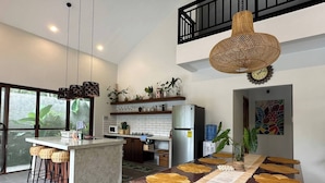 A modern kitchen with a central island, bar stools, and a dining table with a woven placemat.