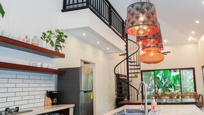 A modern kitchen with a central island, stainless steel appliances, and a spiral staircase.