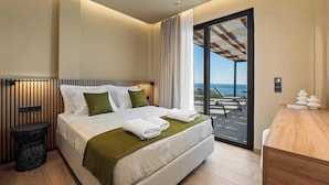 Habitación de hotel moderna con una cama grande, una mesita de noche de madera, un escritorio y un balcón con vistas.
