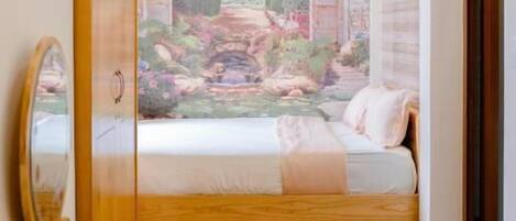 Un dormitorio con cama, cómoda de madera, espejo y un mural de un paisaje.