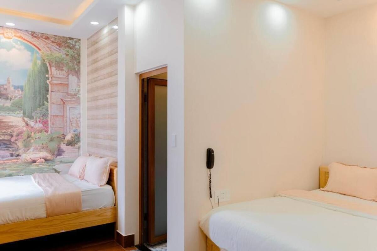 A bedroom with two beds, a mural on the wall, and a phone on the wall.