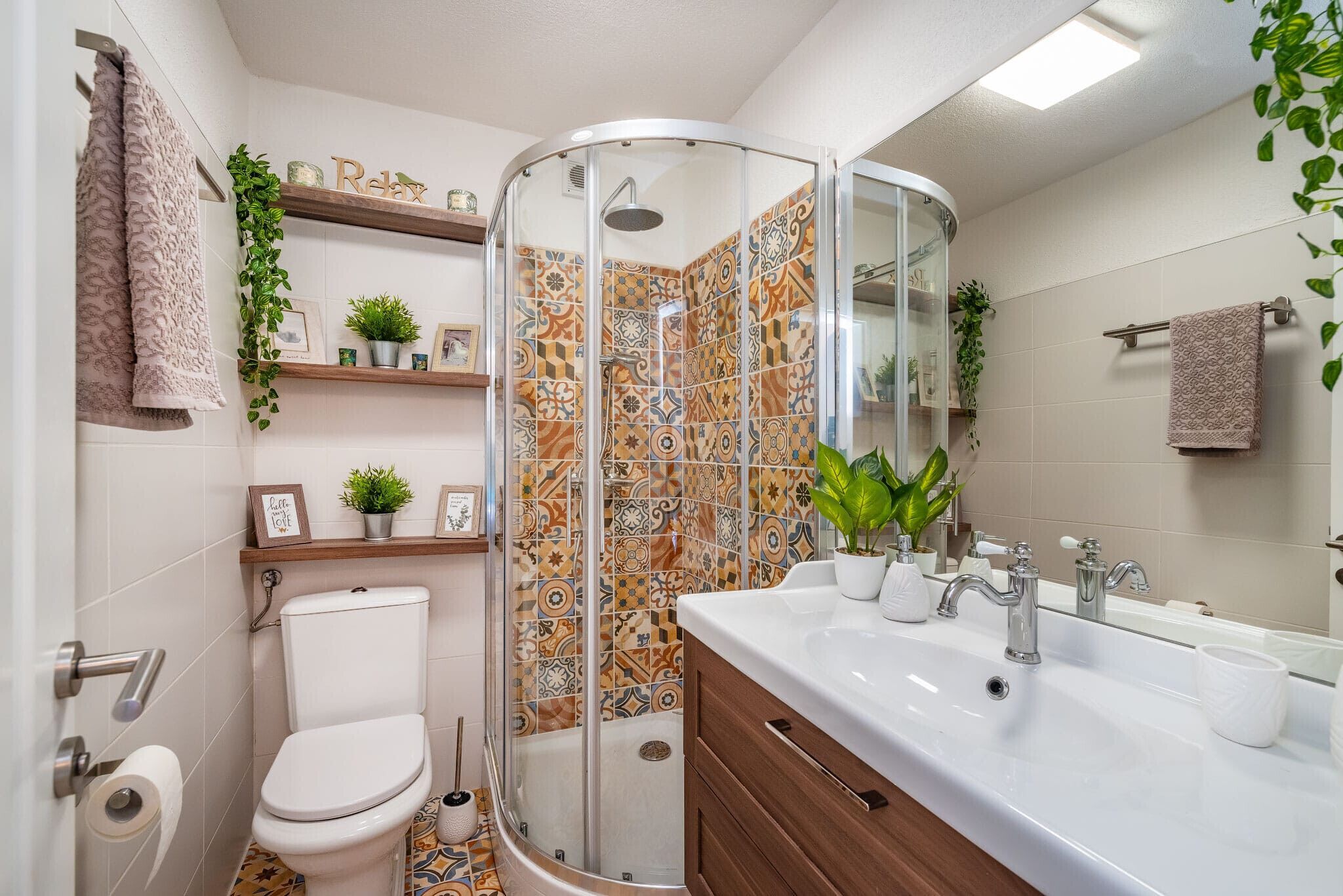 A bathroom with a shower, toilet, sink, and decorative tiles.
