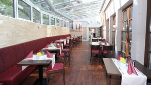 Un restaurante con una barra larga, cabinas, ventanas amplias y un techo alto con tragaluces.