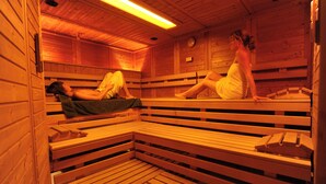 Una sauna con bancos de madera y toalleros, y un reloj en la pared.