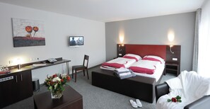 A hotel room with a bed, bedside tables, a desk, a chair, a TV, and a painting on the wall. - Landhotel Gasthof Krone (Kupferzell)