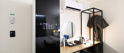 Ein Hotelzimmer mit einem Bett, einem Schreibtisch mit Spiegel, einem Kleiderhaken und einer Bedienanlage.