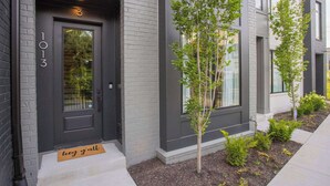 A modern building with a dark gray door marked "1013" and a "hey gall" mat at the entrance. - Luxury Nashville - Rooftop, FireTable & City Views (Nashville)