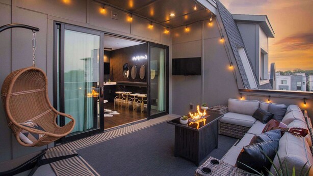 A modern balcony with a hanging chair, a sofa, and a small fire feature. - Luxury Nashville - Rooftop, FireTable & City Views (Nashville)