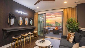 A modern interior with a bar area, seating, and a view of the sunset through large glass doors. - Luxury Nashville - Rooftop, FireTable & City Views (Nashville)