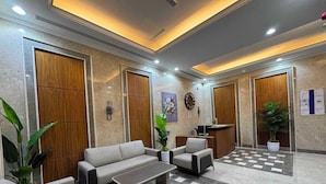A lobby with a checkered floor, a reception desk, a sofa, a coffee table, and potted plants. - Luxury Oasis Apartments in Barsha Heights (Dubai)