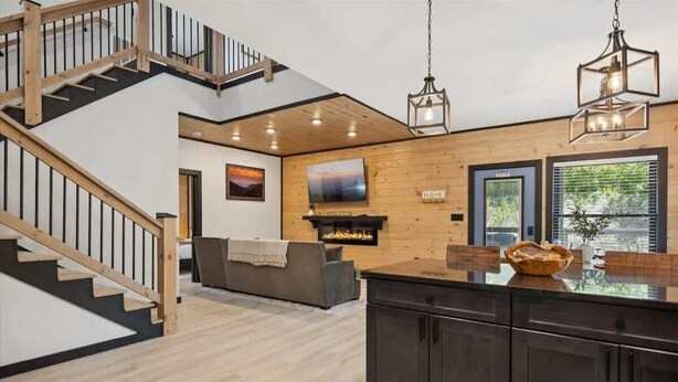 A modern kitchen with dark cabinets, a wooden island, and a fireplace. - Villa De Luxe by Beyond Expectations: Cabin w/ Indoor Pool, Hot Tub & Game Room (Pigeon Forge)
