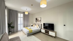 Une chambre moderne avec un lit, une télévision et une grande fenêtre avec des rideaux.