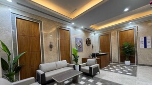 Un hall d’entrée avec un sol à carreaux, un comptoir d’accueil, un canapé, une table basse et deux fauteuils.