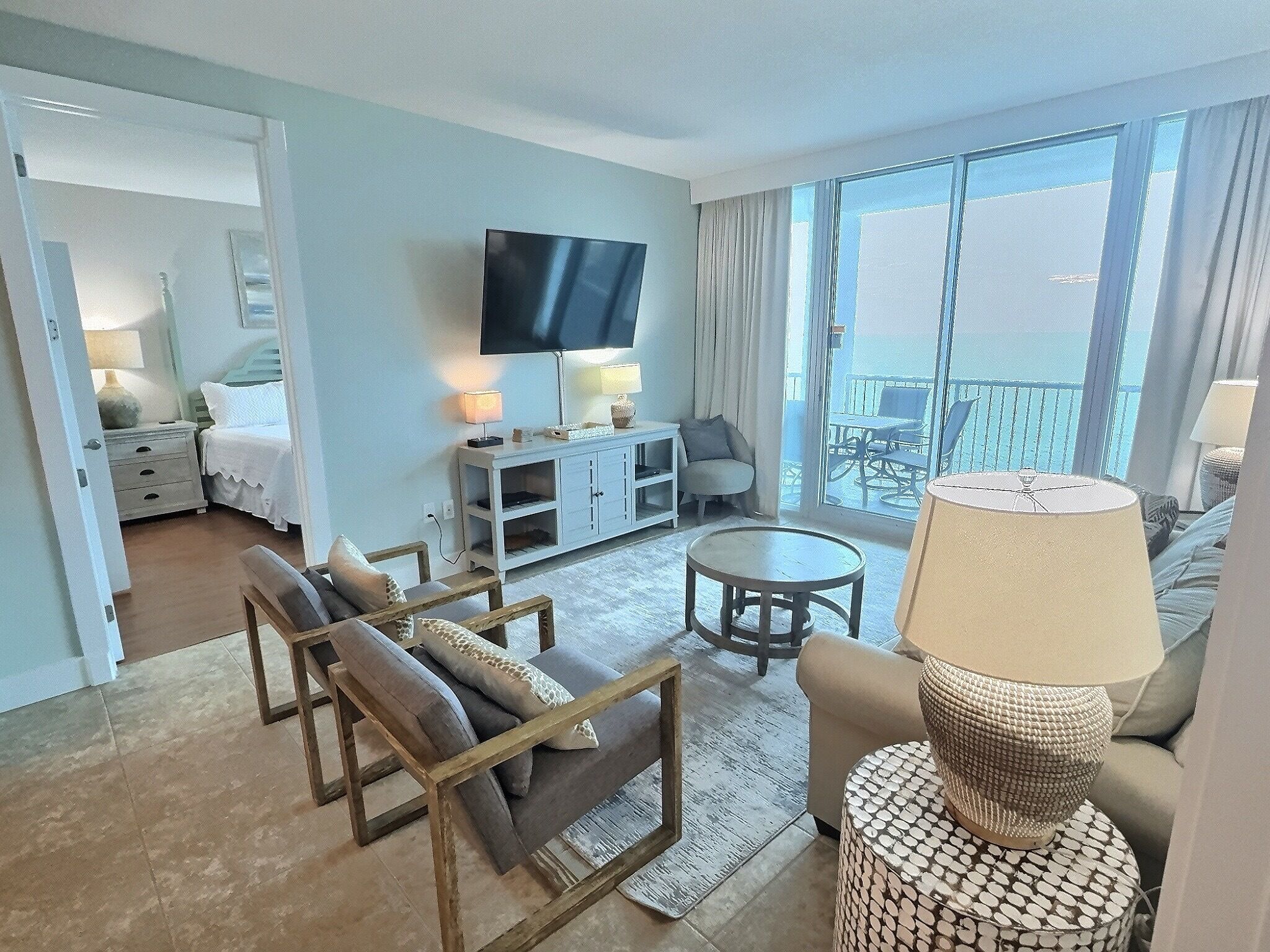 Habitación de hotel con cama, televisión, zona de estar con mesa y sillas, y balcón con vistas.