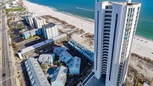 Een kusthotel met uitzicht op het strand, met meerdere hoge gebouwen en een parkeerplaats.