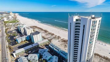 Un hotel costero con vista a la playa, que cuenta con varios edificios altos y un estacionamiento.