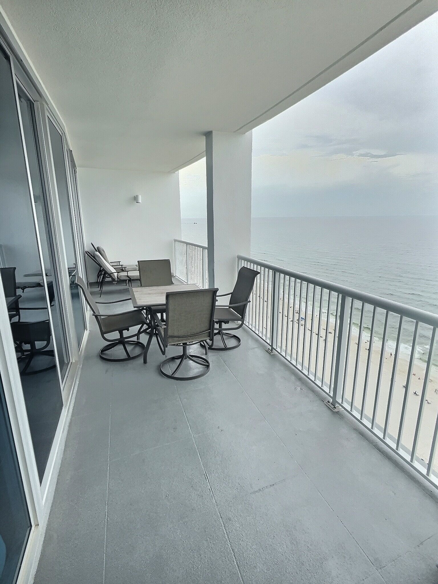 Un balcón con mesa y sillas, con vista a la playa.