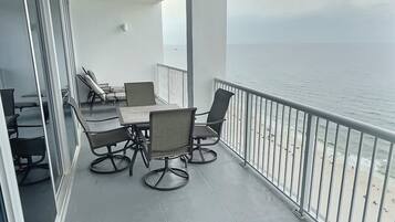 Un balcón con mesa y sillas, con vista a la playa.
