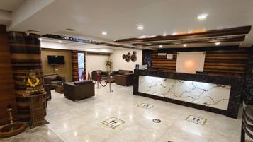 Un moderno vestíbulo de hotel con una recepción, zona de estar y una estatua.