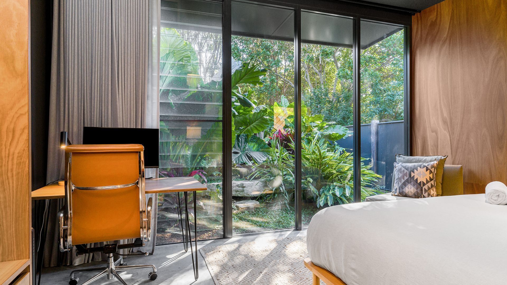 Een moderne hotelkamer met een grote schuifdeur die uitkomt op een tuin.