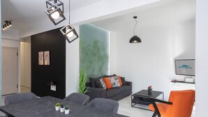 Un salon moderne avec un canapé foncé, une table à manger et un fauteuil orange vif.