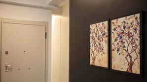 Un couloir avec une porte blanche et deux œuvres d’art encadrées accrochées au mur.