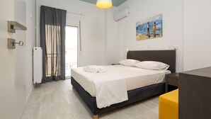 Une chambre à coucher avec un lit, une table de chevet, une lampe, un tableau au mur et une fenêtre avec des rideaux.