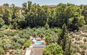 Eine Villa, umgeben von dichter Vegetation, mit Swimmingpool und Außenbereich mit Sitzgelegenheiten.