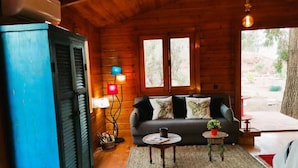 Ett mysigt rum i en stuga med väggar av timmer, inrett med en soffa, ett litet bord och en lampa.