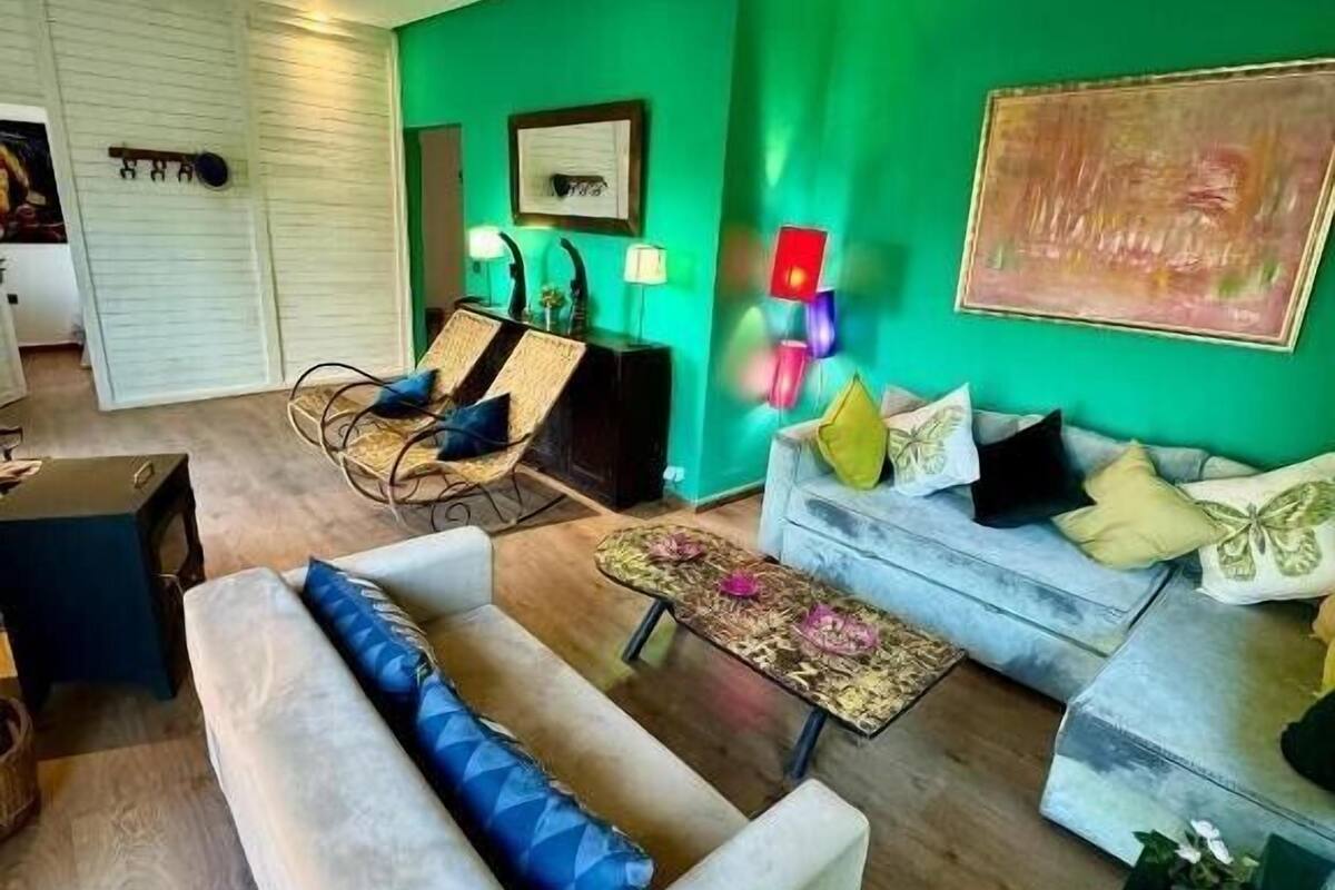 A living room with a green accent wall, a sofa, a coffee table, and a chair.