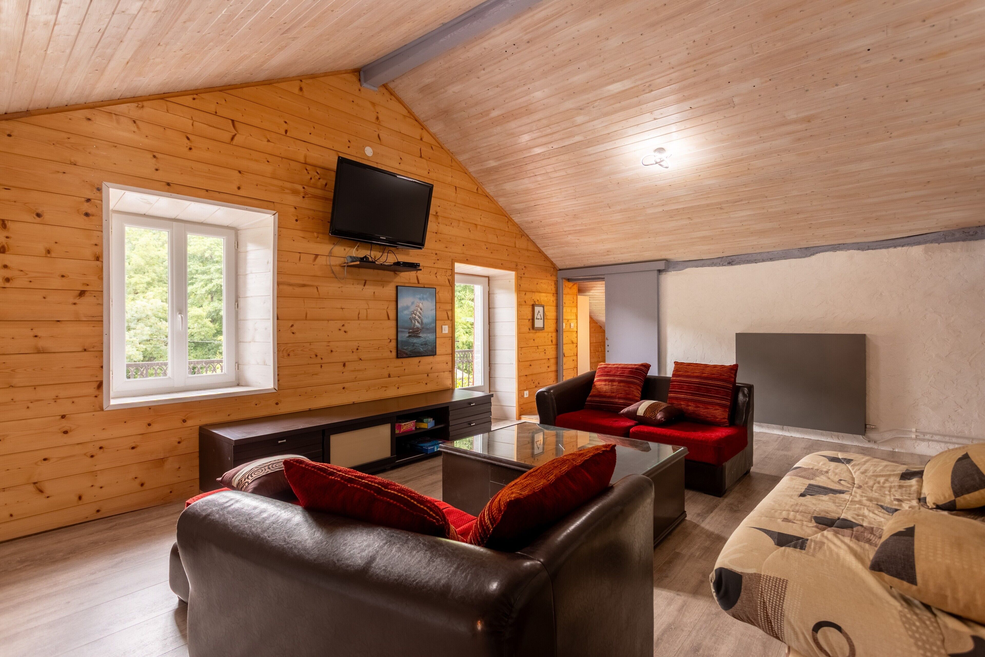 A wooden interior with a TV, sofa, and fireplace.