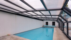A swimming pool with a glass ceiling, a tiled floor, and a bench. - Holiday Home 'À Isturits Avec Piscine' with Shared Pool, Private Terrace and Wi-Fi (Isturits)