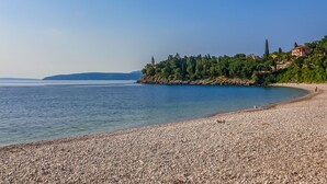 A pebble beach with a clear view of the sea and a forested hillside in the background. - Lilly 2 by Interhome (Lovran/Medveja)