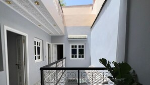 A courtyard with ornate ceiling and patterned floor tiles, a potted plant, and a staircase leading to an upper level. - Riad El Ghali Prestige (Marrakech)