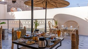 An outdoor dining area with a table set for breakfast, including plates, cups, and a kettle. - Riad El Ghali Prestige (Marrakech)