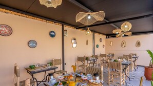 A restaurant with outdoor seating, featuring woven chairs and tables, decorative plates, and hanging lights. - Riad El Ghali Prestige (Marrakech)