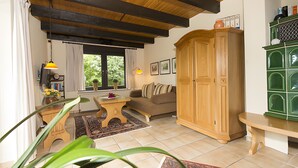 A living room with a sofa, wooden cabinet, and a window with curtains.